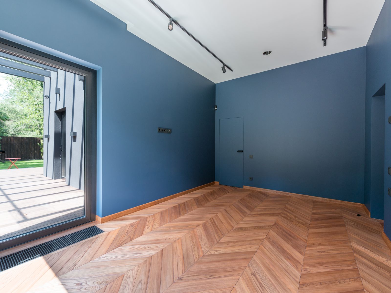 Parquet en point de Hongrie posé dans une pièce vide aux murs bleus.