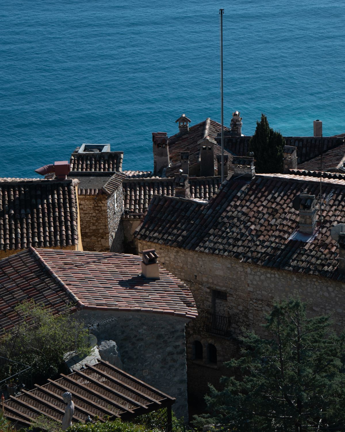 Les toits de tuile d’un village méditerranéen en pierre claire, serrés les uns contre les autres au-dessus de la mer.